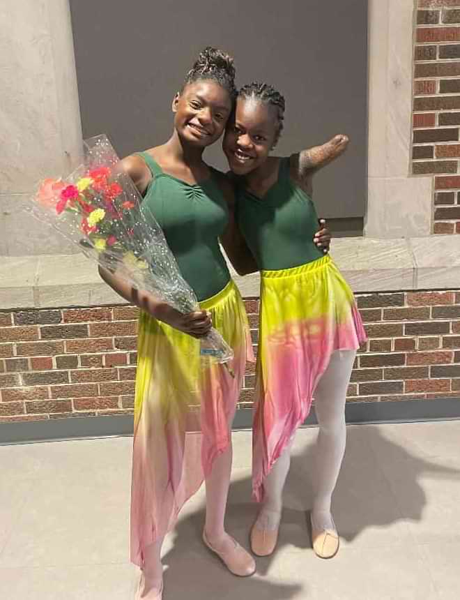 Two Young Ballet Students Posing With Flowers